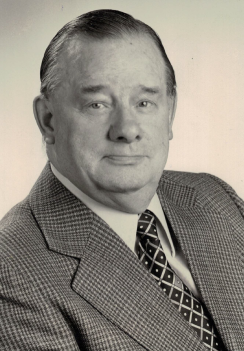 Schwarz-Weiß Porträt eines Mannes in Anzug und Krawatte mit neutralem Gesichtsausdruck.