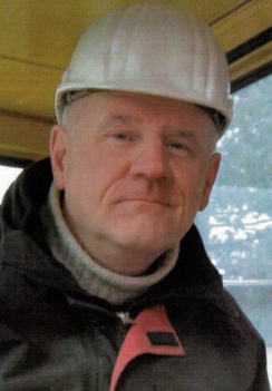 Mann mit Bauhelm und Winterjacke blickt freundlich in die Kamera.